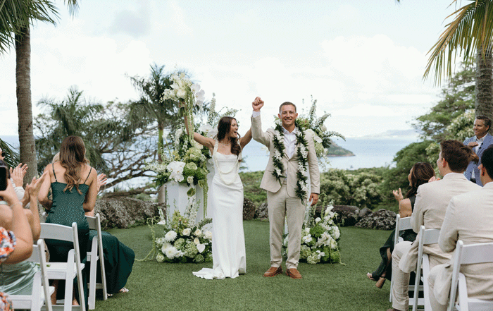 Couple exchanging vows under garden canopy at Kualoa Ranch